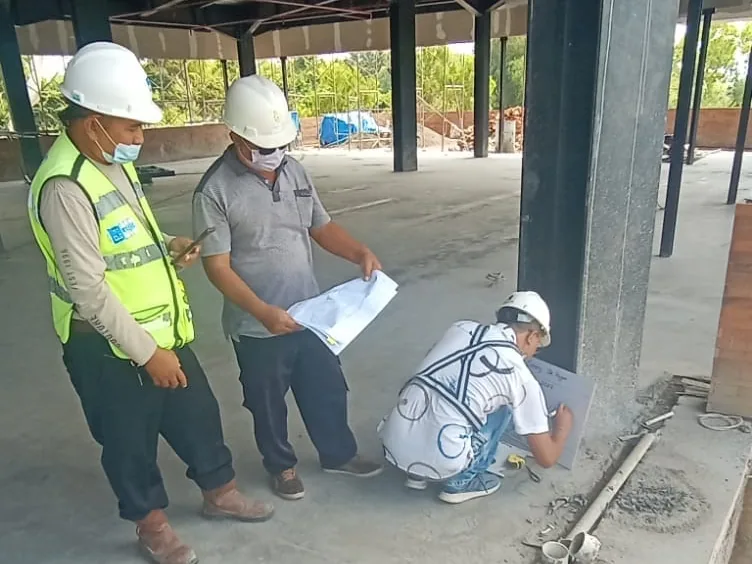 Tim membaca gambar kerja di area struktur bangunan